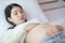 Young beautiful pregnant woman lie down and touching belly on bed at home. Pregnancy, motherhood, love and expectation concept