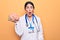 Young beautiful psychiatrist woman wearing stethoscope holding brain over yellow background scared and amazed with open mouth for