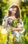 Young beautiful red hair woman holding a wild flowers bouquet in a sunny day. Portrait of attractive long hair female with flowers