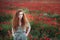 Young beautiful red-hear girl in red poppy field