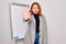 Young beautiful redhead businesswoman doing business presentation using magnetic board doing stop sing with palm of the hand