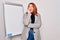 Young beautiful redhead businesswoman doing business presentation using magnetic board looking stressed and nervous with hands on