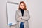 Young beautiful redhead businesswoman doing business presentation using magnetic board skeptic and nervous, disapproving
