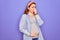 Young beautiful redhead pregnant woman expecting baby over isolated purple background smelling something stinky and disgusting,