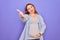 Young beautiful redhead pregnant woman expecting baby over isolated purple background smiling friendly offering handshake as
