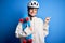 Young beautiful redhead skateboarder woman wearing safety helmet holding skate very happy pointing with hand and finger to the