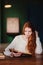 Young beautiful redhead student woman reading book in university library