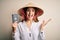 Young beautiful redhead tourist woman wearing asian traditional hat holding usa passport very happy and excited, winner expression