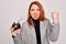 Young beautiful redhead woman drinking argentina mate beverage over white background annoyed and frustrated shouting with anger,