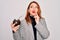 Young beautiful redhead woman drinking argentina mate beverage over white background serious face thinking about question, very