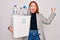 Young beautiful redhead woman recycling holding trash can with plastic bottles to recycle screaming proud and celebrating victory