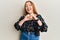 Young beautiful redhead woman wearing casual floral clothes smiling in love doing heart symbol shape with hands