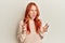 Young beautiful redhead woman wearing casual winter sweater crazy and mad shouting and yelling with aggressive expression and arms