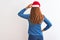 Young beautiful redhead woman wearing christmas hat over isolated background Backwards thinking about doubt with hand on head