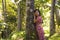 Young beautiful and relaxed Asian Chinese woman in elegant summer dress enjoying serene the beauty of nature leaning dreamy on