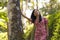 Young beautiful and relaxed Asian Korean woman in elegant summer dress enjoying serene the beauty of nature leaning dreamy on tree