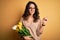 Young beautiful romantic woman with curly hair holding bouquet of yellow tulips Pointing aside worried and nervous with