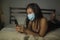 Young beautiful scared and overwhelmed Asian Chinese woman in protective mask checking online news worried about coronavirus