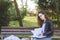 Young beautiful school or college girl with eyeglasses sitting on the bench in the park reading the books and study for exam