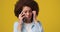 Young beautiful serious frustrated African american woman talking on the phone answering phone call over yellow orange
