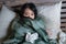 Young beautiful sick and exhausted Asian Chinese woman suffering cold and flu holding thermometer having temperature lying on bed