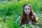 Young beautiful Slavic girl with long hair and Slavic ethnic attire lies in the grass in a summer forest