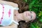 Young beautiful Slavic girl with long hair and Slavic ethnic attire lies in the grass in a summer forest