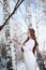 Young beautiful Slavic girl with long hair and Slavic ethnic attire posing in a spring forest near a birch tree with ritual bread