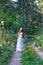 Young beautiful Slavic girl with long hair and Slavic ethnic attire walking along the trail in the summer forest