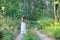 Young beautiful Slavic girl with long hair and Slavic ethnic attire walking along the trail in the summer forest