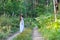 Young beautiful Slavic girl with long hair and Slavic ethnic attire walking along the trail in the summer forest