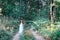 Young beautiful Slavic girl with long hair and Slavic ethnic attire walking along the trail in the summer forest