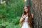 A young beautiful Slavic girl with long hair and Slavic ethnic dress stands in a summer forest with a ritual dagger in her hands