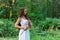 A young beautiful Slavic girl with long hair and Slavic ethnic dress stands in a summer forest with a ritual dagger in her hands