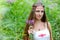 A young beautiful Slavic girl with long hair and a Slavic ethnic dress stands among the tall undergrowth in the summer forest and