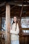 Young beautiful Slavic girl with long hair and Slavic ethnic dress stands in a wooden ethnic gazebo