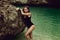 Young beautiful slylish woman in jewelry posing in the water near the rock
