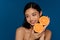 Young beautiful smiling asian woman with two oranges halves