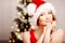 Young beautiful smiling santa woman near the Christmas tree. Fashionable luxury girl celebrating New Year. Beauty luxury trendy b