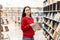 A young beautiful smiling woman poses with a book in her hands, against the background of shelves with books. The concept of