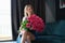 Young beautiful smiling woman is sitting with large bouquet of roses