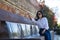 Young and beautiful South American woman with sunglasses and white shirt, on vacation in Europe sitting by a fountain, throwing