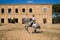 Young, beautiful Spanish woman on a brown horse in the countryside. The horse raises its front legs. She is doing dressage