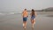 Young beautiful sports couple runs barefoot on sandy sea beach.