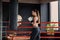 Young beautiful sports girl in sportswear and boxing gloves hits a punching bag in modern black gym.
