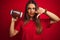 Young beautiful sportswoman holding football ball over isolated red background with angry face, negative sign showing dislike with