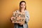 Young beautiful sportswoman holding woman power banner over isolated yellow background cover mouth with hand shocked with shame