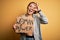 Young beautiful sportswoman holding woman power banner over isolated yellow background with happy face smiling doing ok sign with