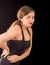 Young beautiful sportwoman suffer cervical pain in her lower back, in black background