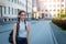 Young beautiful student with backpack on her shoulder goes to school, close-up. Schoolgirl with two braids standing